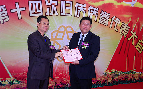省僑聯(lián)領導楊春華（左）向新會區(qū)委副書記增雄偉（右）頒發(fā)名譽主席聘書