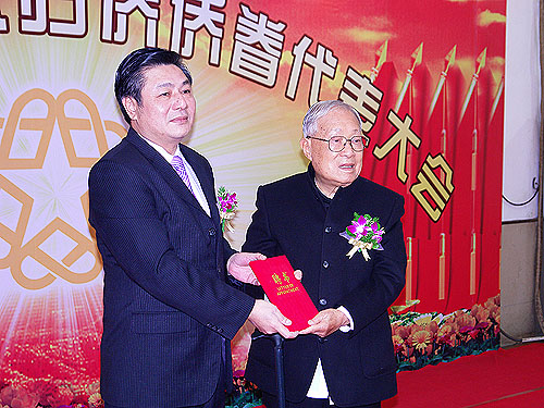新會區(qū)委書記魏志平（左）向新會榮譽市民黃球先生（右）頒發(fā)名譽主席聘書